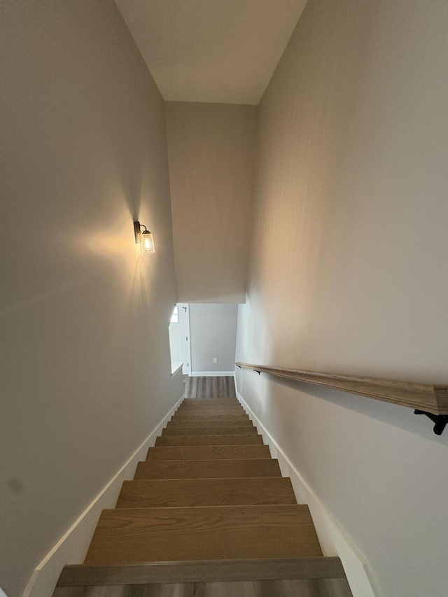 stairway with wood finished floors and baseboards