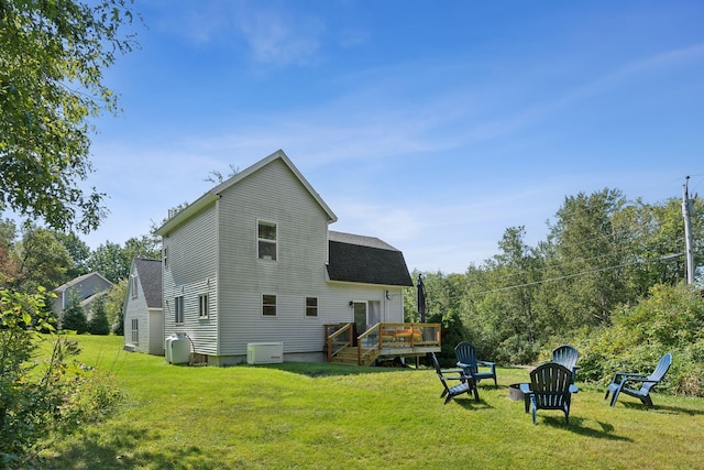 rear view of house featuring a shingled roof, a lawn, and a wooden deck