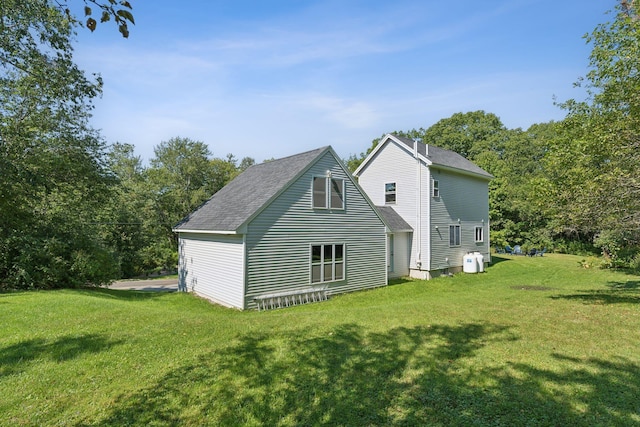 back of property with roof with shingles and a yard