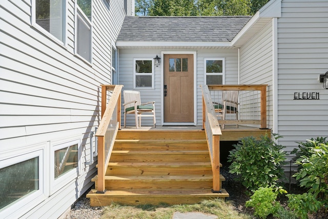 entrance to property with roof with shingles and a wooden deck