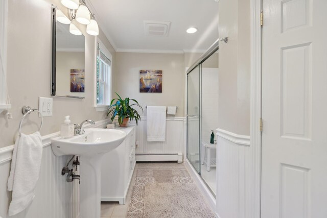 bathroom with a baseboard heating unit, wainscoting, ornamental molding, and a shower stall