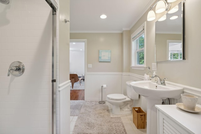 full bathroom featuring a wainscoted wall, tiled shower, toilet, and crown molding