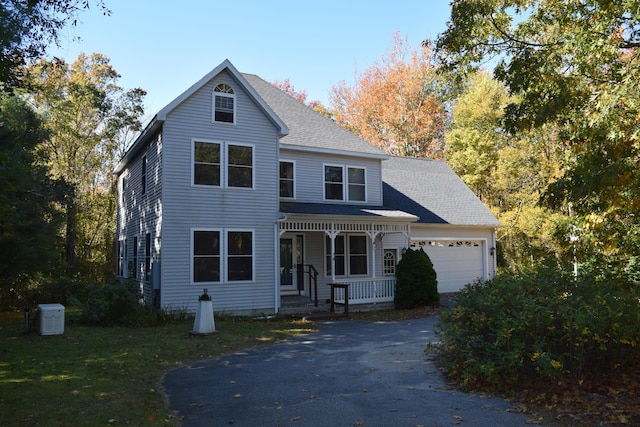 view of front of home with a porch, a shingled roof, an attached garage, driveway, and a front lawn