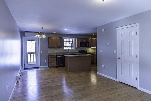 kitchen featuring tasteful backsplash, dark wood-style flooring, hanging light fixtures, and black appliances