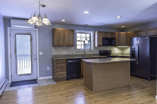 kitchen with a kitchen island, a sink, black appliances, a wall mounted air conditioner, and decorative light fixtures