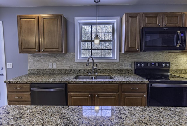 kitchen with a sink, backsplash, light stone countertops, black appliances, and pendant lighting