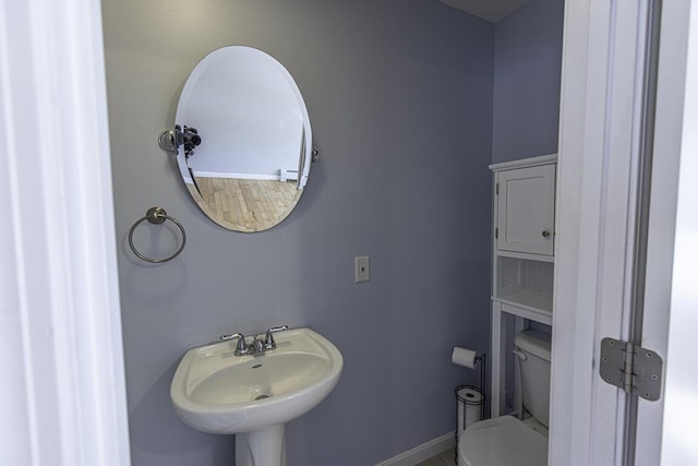 bathroom with a sink, toilet, and baseboards