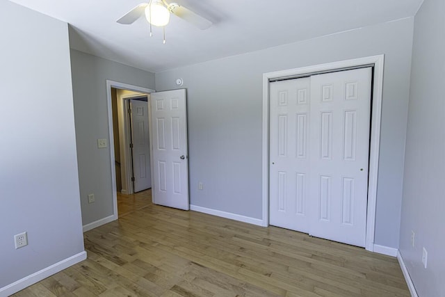 unfurnished bedroom featuring light wood-style floors, ceiling fan, baseboards, and a closet