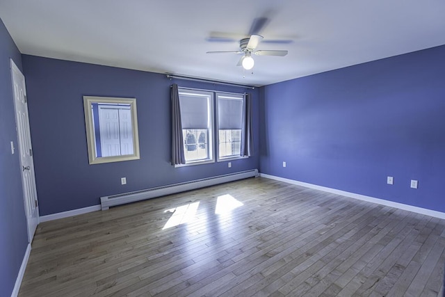 unfurnished room featuring baseboard heating, wood finished floors, a ceiling fan, and baseboards