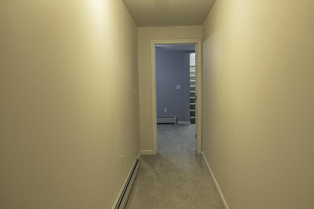 hallway with a baseboard radiator, light carpet, and baseboards