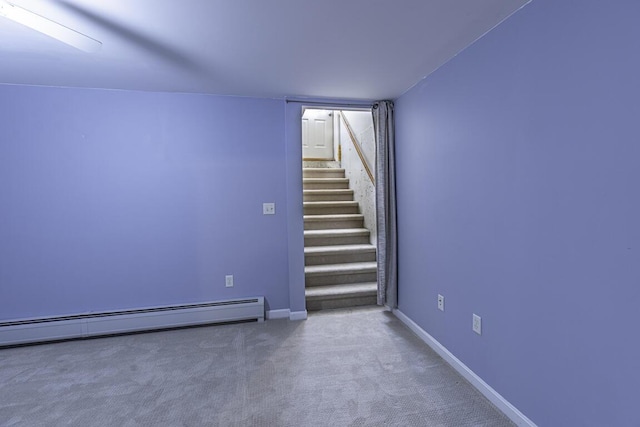 carpeted empty room featuring stairs, a baseboard heating unit, and baseboards