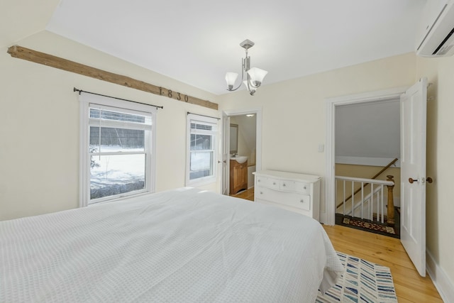 bedroom with a chandelier, an AC wall unit, and light wood-style flooring