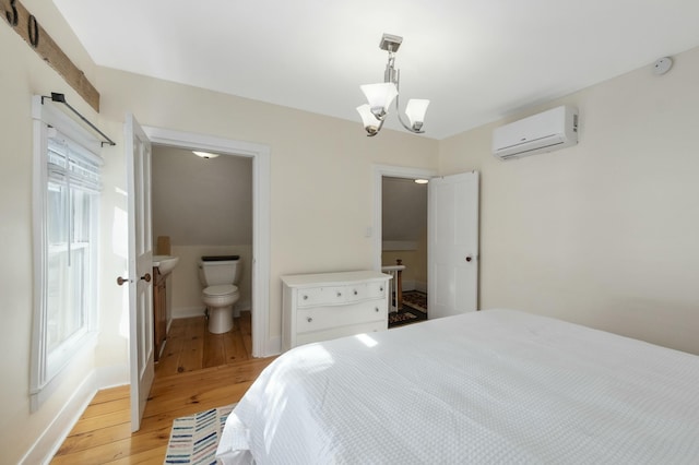 bedroom with light wood-type flooring, baseboards, a chandelier, and an AC wall unit