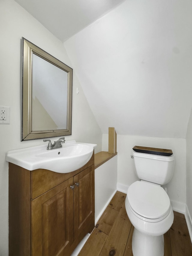 half bath featuring vaulted ceiling, vanity, and wood finished floors