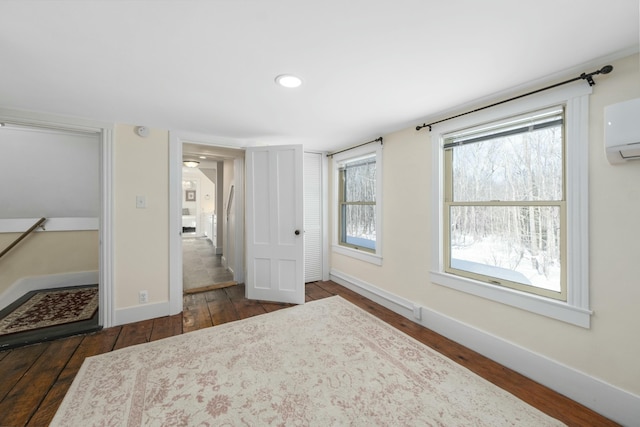 unfurnished bedroom featuring dark wood-style flooring, recessed lighting, a wall mounted AC, and baseboards