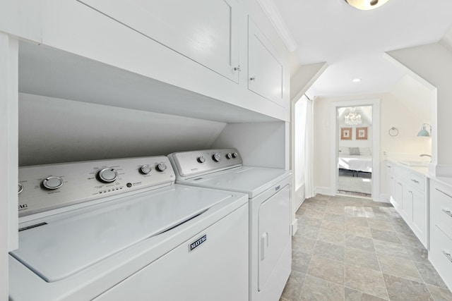 clothes washing area with cabinet space, a sink, and washing machine and clothes dryer