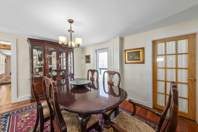 dining area featuring an inviting chandelier, baseboards, and wood finished floors