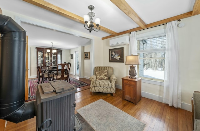 sitting room featuring beam ceiling, a notable chandelier, wood finished floors, a wall mounted air conditioner, and baseboards