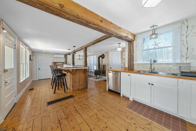 kitchen featuring a sink, visible vents, white cabinets, dishwasher, and pendant lighting