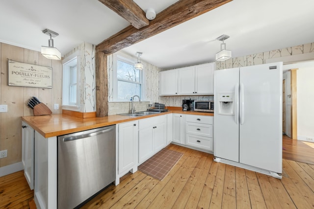 kitchen with decorative light fixtures, wooden counters, appliances with stainless steel finishes, white cabinets, and a sink