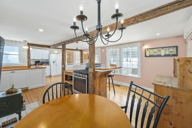 dining area with light wood-type flooring, an inviting chandelier, and beam ceiling