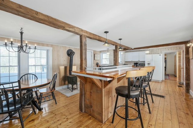 kitchen with a peninsula, white cabinets, hanging light fixtures, beam ceiling, and white fridge with ice dispenser