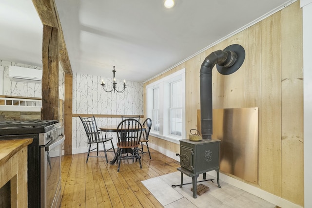 dining room with a wood stove, an inviting chandelier, light wood-style flooring, and baseboards