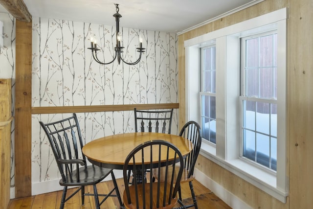 dining space featuring wood finished floors, baseboards, an inviting chandelier, and wallpapered walls