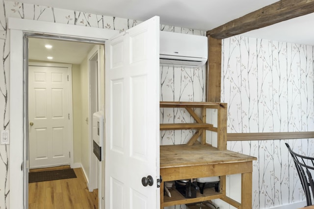 corridor with a wall mounted air conditioner, wood finished floors, beam ceiling, and wallpapered walls