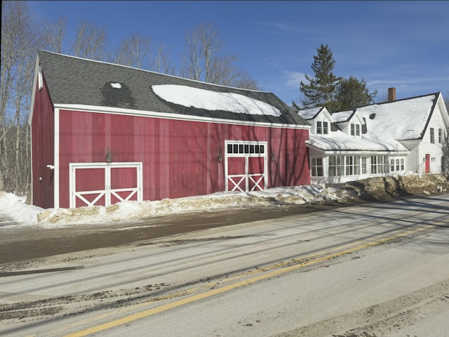 snow covered structure featuring an outbuilding and a barn