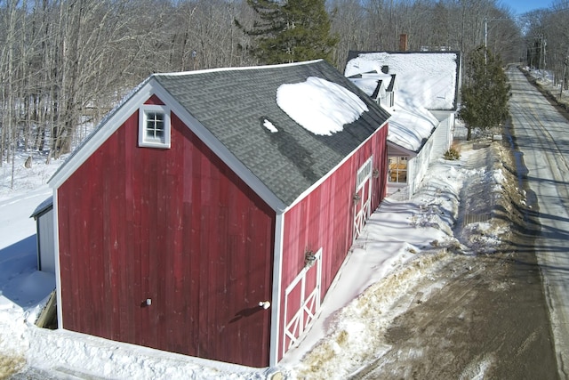 snow covered structure with an outbuilding