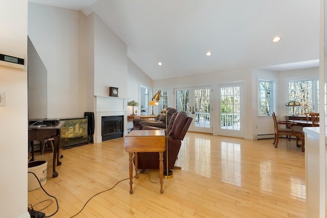 23 Sunny Acres Ln, Boothbay, ME 04537 - living area with a baseboard radiator, a glass covered fireplace, light wood finished floors, high vaulted ceiling, and recessed lighting