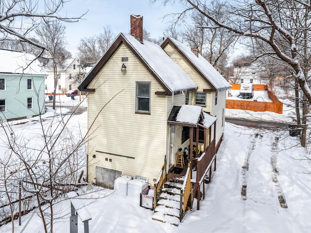 snow covered property with a chimney