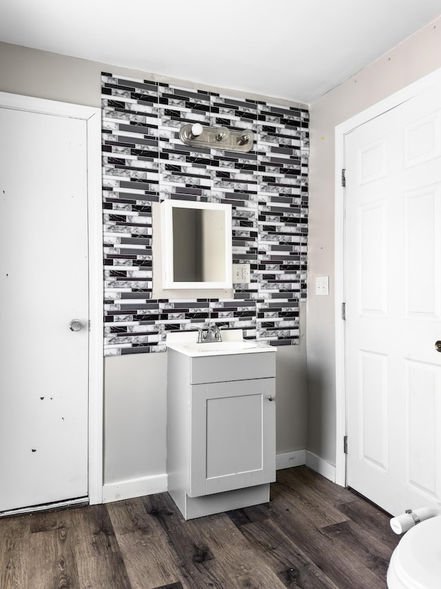 bathroom with baseboards, vanity, decorative backsplash, and wood finished floors