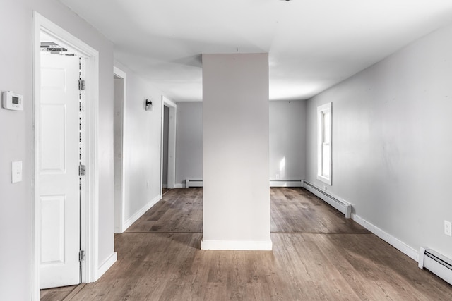 unfurnished room featuring dark wood-style floors, baseboards, and baseboard heating