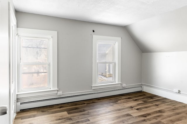 bonus room featuring a textured ceiling, a baseboard heating unit, vaulted ceiling, and dark wood finished floors