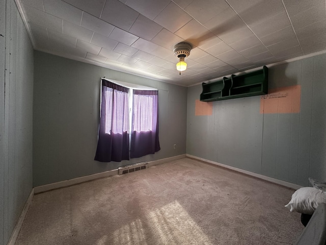 spare room featuring carpet, visible vents, crown molding, and baseboards