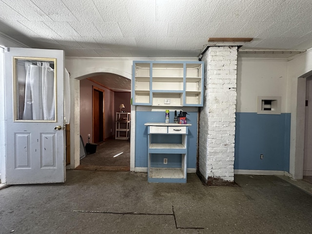 interior space featuring arched walkways, a textured ceiling, and baseboards