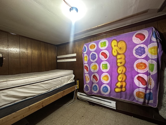 bedroom featuring a baseboard heating unit, wooden walls, and tile patterned floors