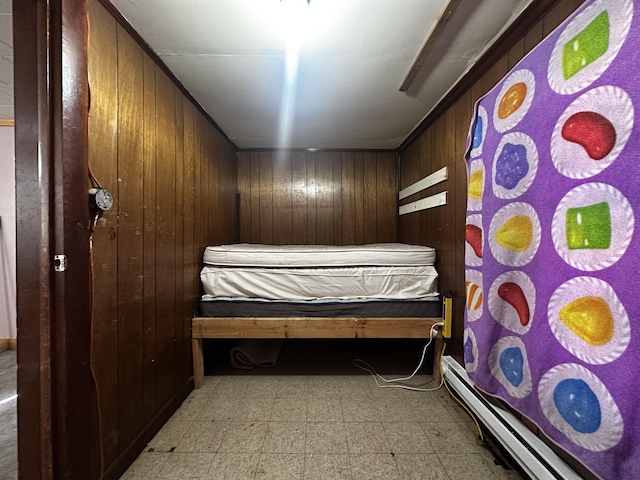 bedroom featuring light floors, a baseboard radiator, and wooden walls