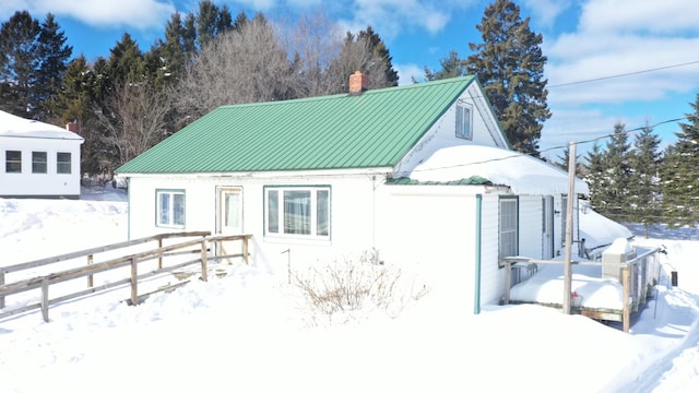 exterior space featuring a standing seam roof, a chimney, fence, and metal roof