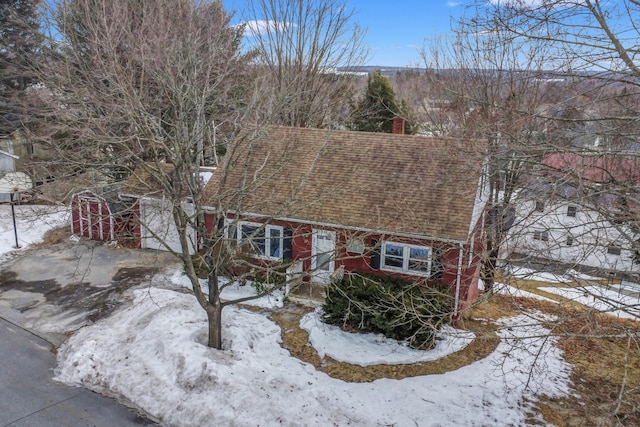 view of front of house with brick siding, a chimney, and roof with shingles