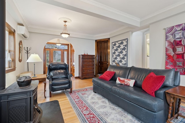 living area with arched walkways, a wall unit AC, light wood-style floors, and ornamental molding