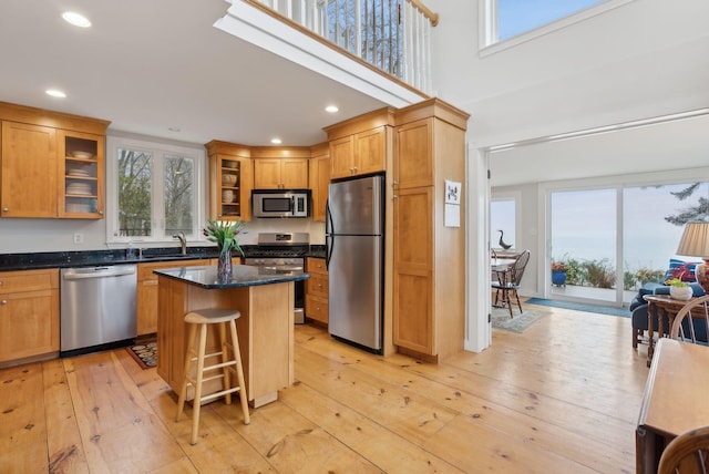 kitchen with stainless steel appliances, a sink, glass insert cabinets, recessed lighting, and a breakfast bar area