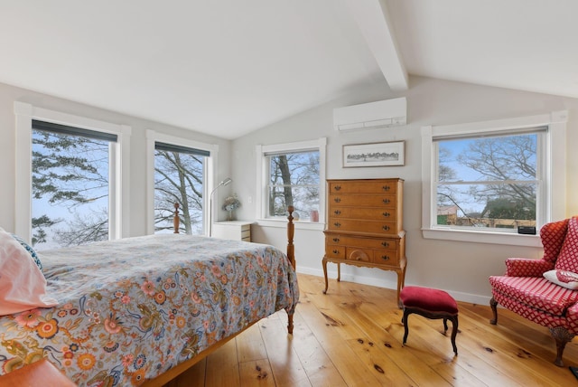 bedroom with a wall unit AC, light wood-style floors, and baseboards