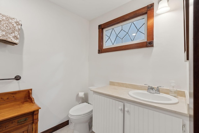 half bath with vanity, toilet, and baseboards
