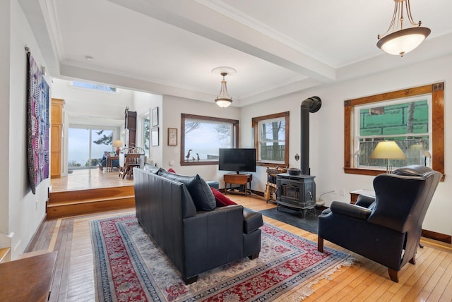 living room with a wood stove, light wood-style flooring, ornamental molding, and baseboards