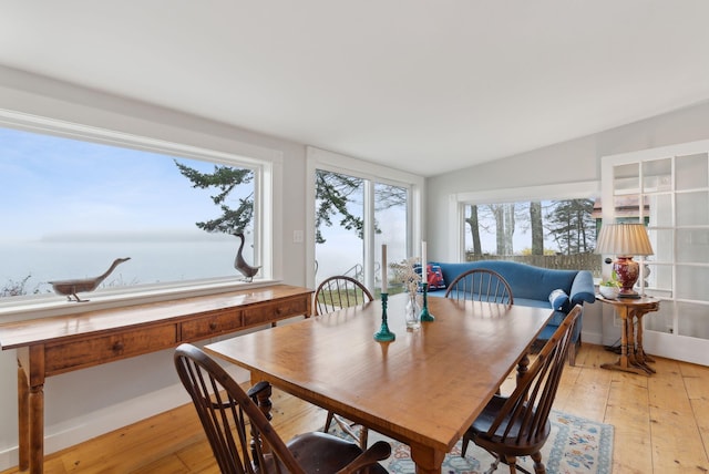 dining room featuring light wood finished floors and vaulted ceiling