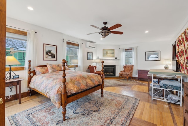 bedroom featuring an AC wall unit, multiple windows, wood-type flooring, and recessed lighting