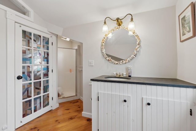 full bath featuring wood finished floors, a stall shower, vanity, and baseboards